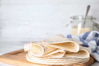 Photo of Wooden board with corn tortillas on table, space for text. Unleavened bread