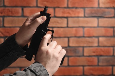 Armed robbery. Dangerous criminal with gun near brick wall, closeup. Space for text