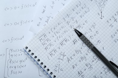 Photo of Notebook with different mathematical formulas and pen, top view