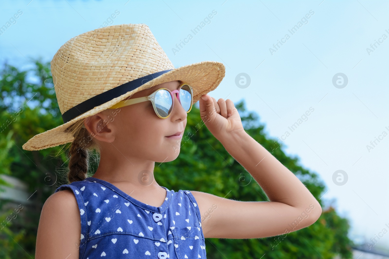 Photo of Little girl wearing sunglasses and hat at beach on sunny day