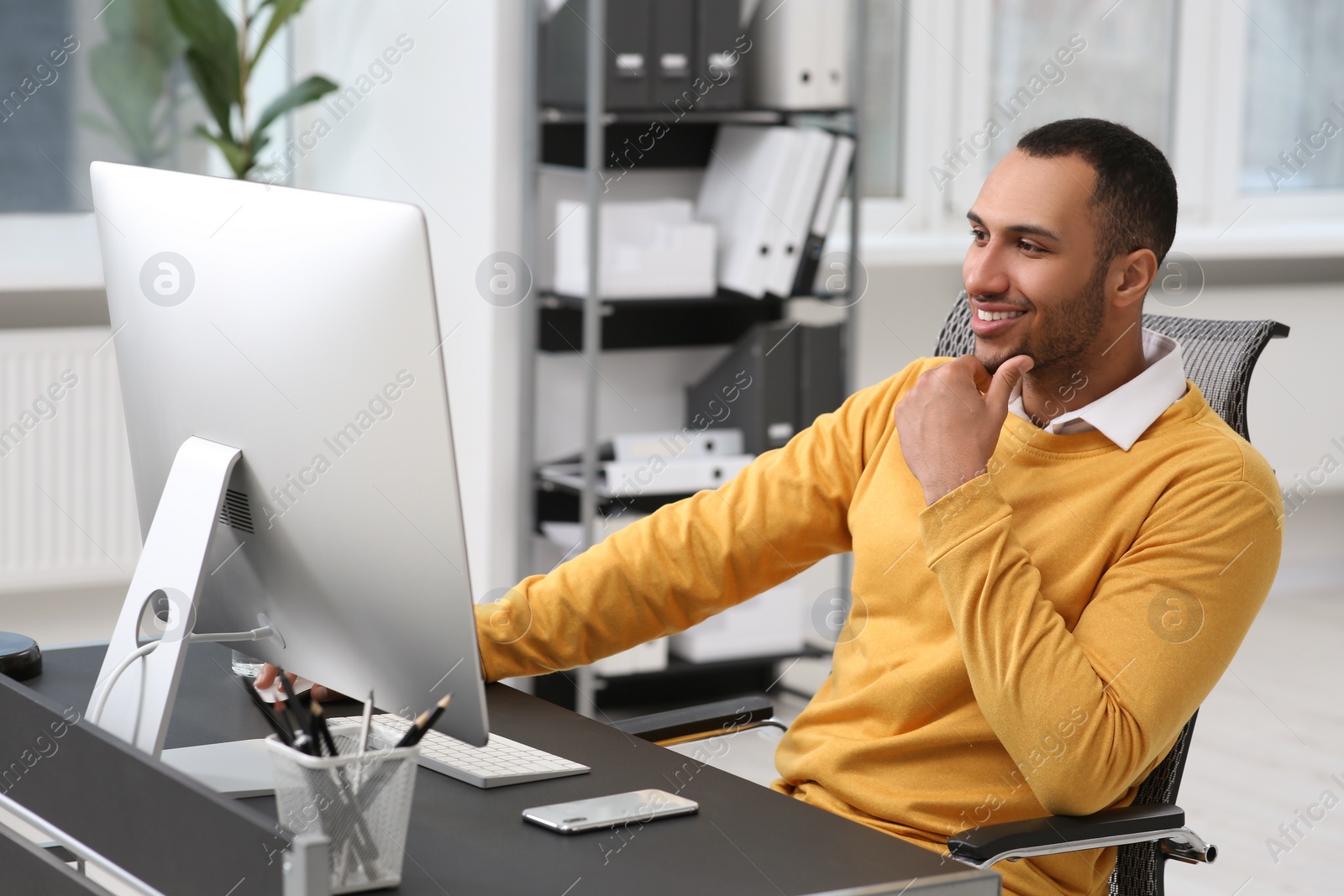 Photo of Young man working on computer at table in office