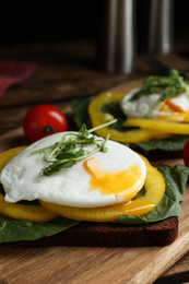 Photo of Delicious poached egg sandwich served on wooden board, closeup