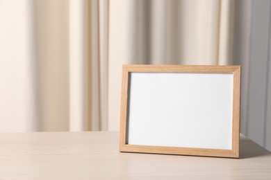 Photo of Empty square frame on white wooden table indoors, space for text