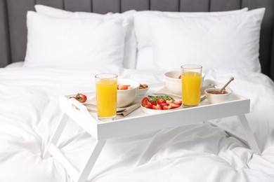 Photo of Tray with tasty breakfast on bed at home