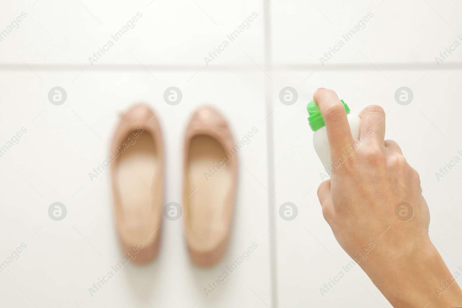 Photo of Woman spraying deodorant over pair of shoes at home, closeup. Space for text