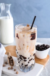 Photo of Bubble milk tea with tapioca balls on table against blue background
