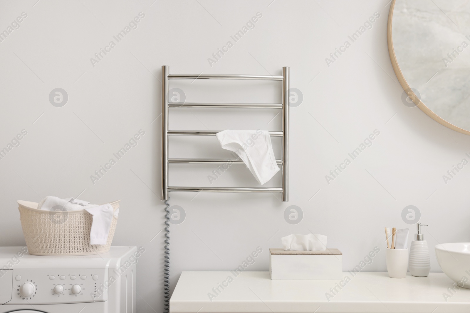 Photo of Heated towel rail with underwear on white wall in bathroom