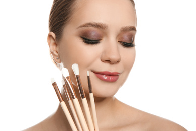 Beautiful woman with makeup brushes on white background