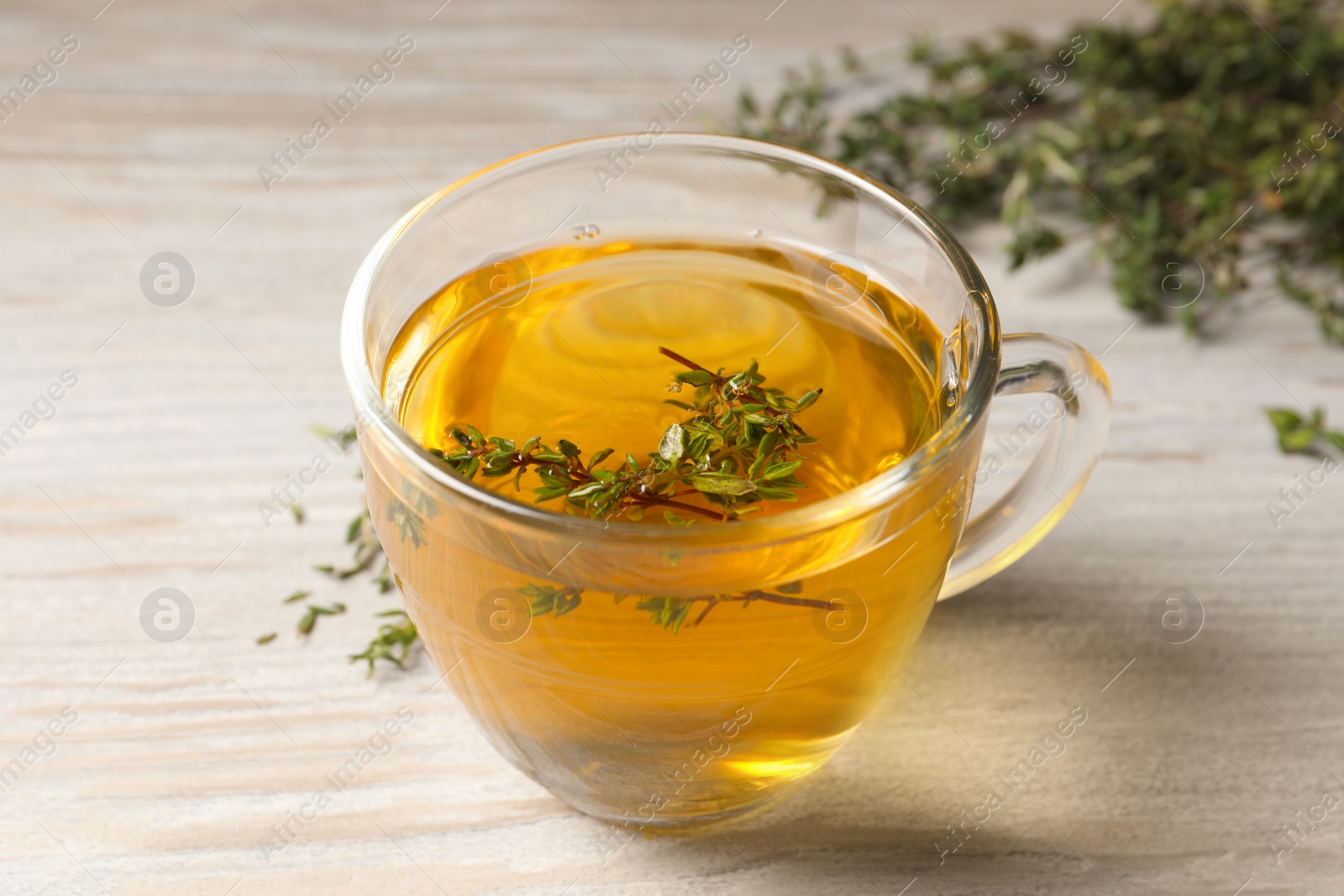 Photo of Cup of fresh thyme tea on wooden table, closeup