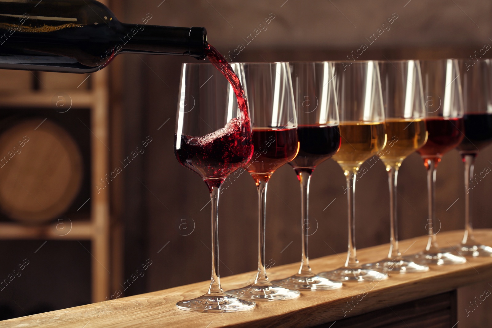 Photo of Pouring wine from bottle into glass in cellar