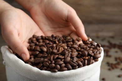 Photo of Woman taking roasted coffee beans from bag, closeup