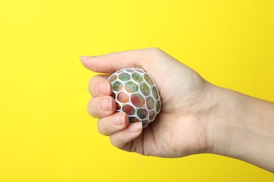 Photo of Woman holding colorful slime on yellow background, closeup. Antistress toy