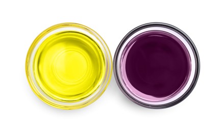 Photo of Glass bowls with yellow and purple food coloring on white background, top view