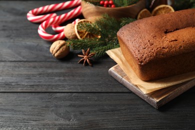 Delicious gingerbread cake and Christmas items on black wooden table, space for text