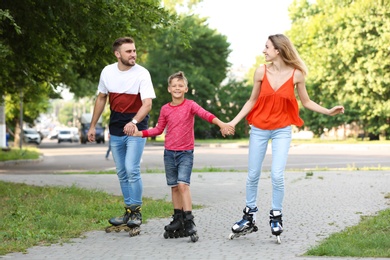 Photo of Young happy family roller skating on city street