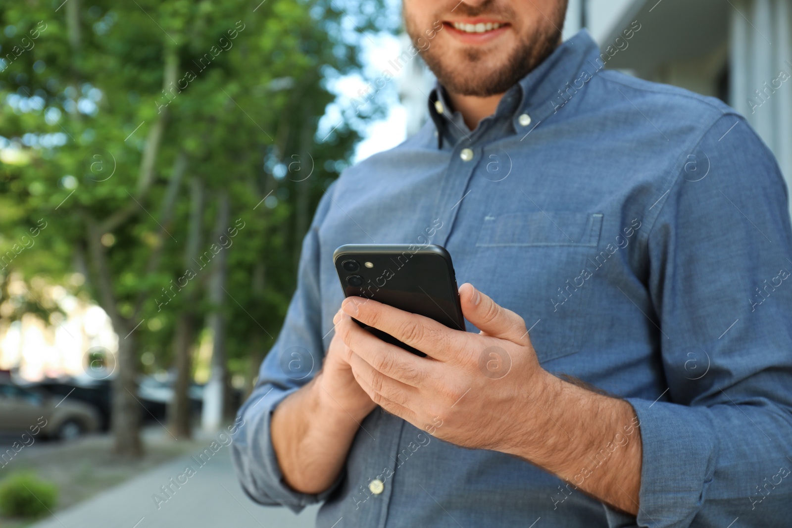 Photo of Young man with smartphone on city street, closeup