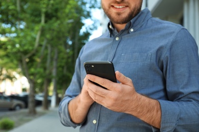 Photo of Young man with smartphone on city street, closeup