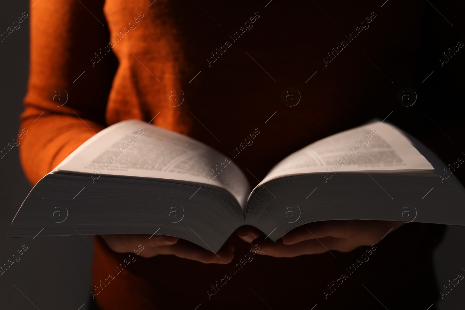 Photo of Woman reading Bible against black background, closeup