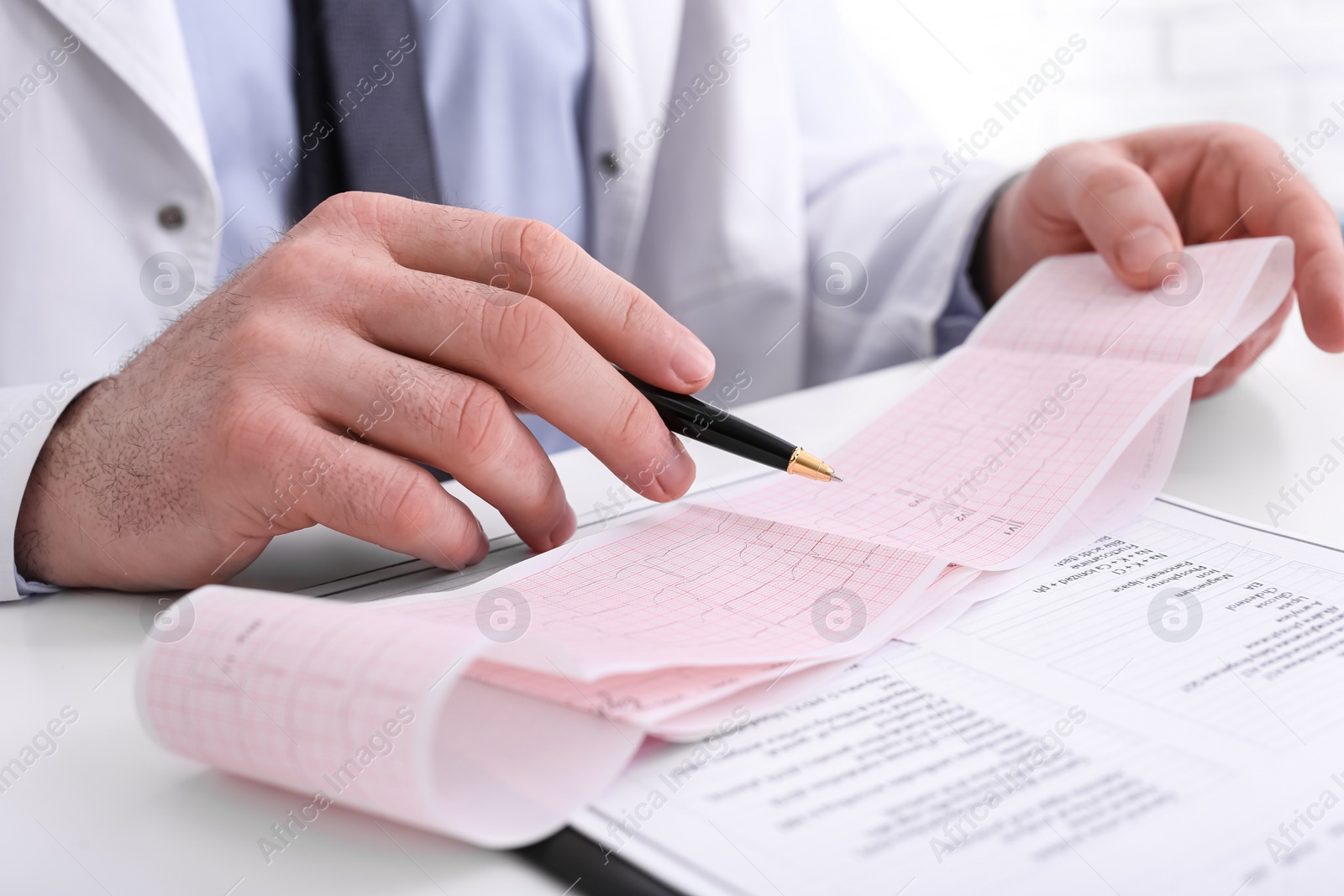 Photo of Doctor examining cardiogram at table in clinic, closeup