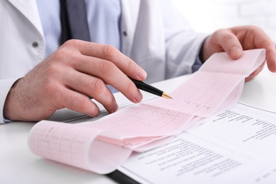 Photo of Doctor examining cardiogram at table in clinic, closeup