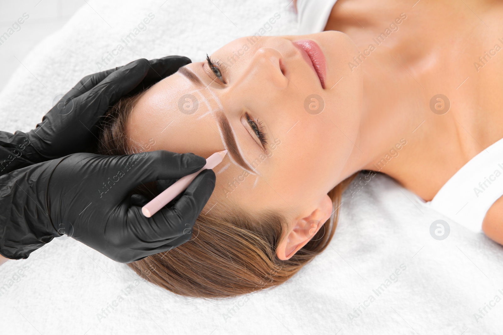 Photo of Young woman undergoing eyebrow correction procedure in salon