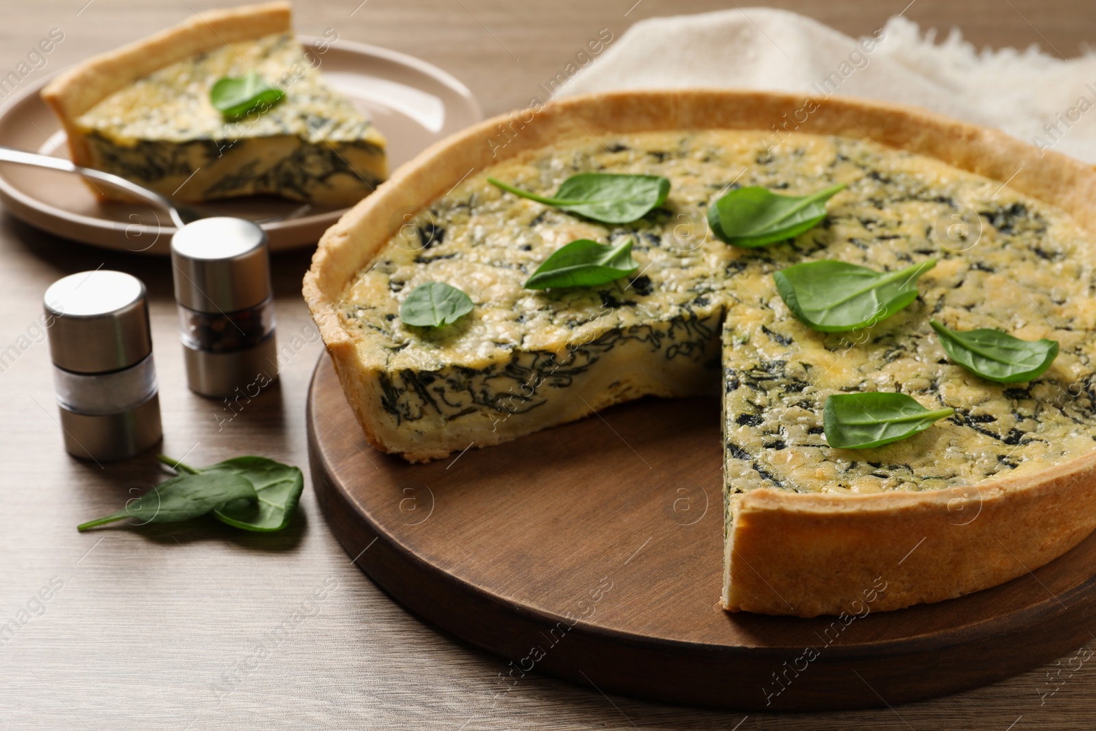 Photo of Delicious homemade spinach pie and spices on wooden table