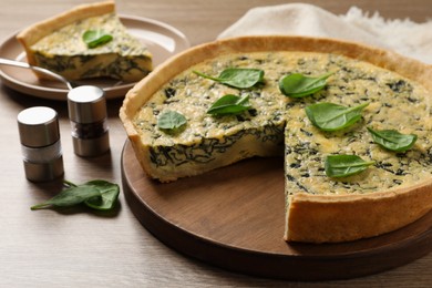 Delicious homemade spinach pie and spices on wooden table