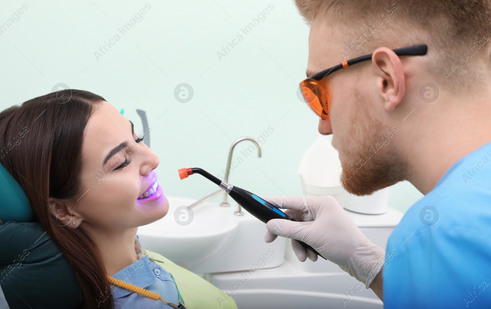 Photo of Professional dentist working with patient in modern clinic. Teeth whitening