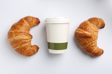 Photo of Delicious fresh croissants and paper cup with coffee on light background, flat lay