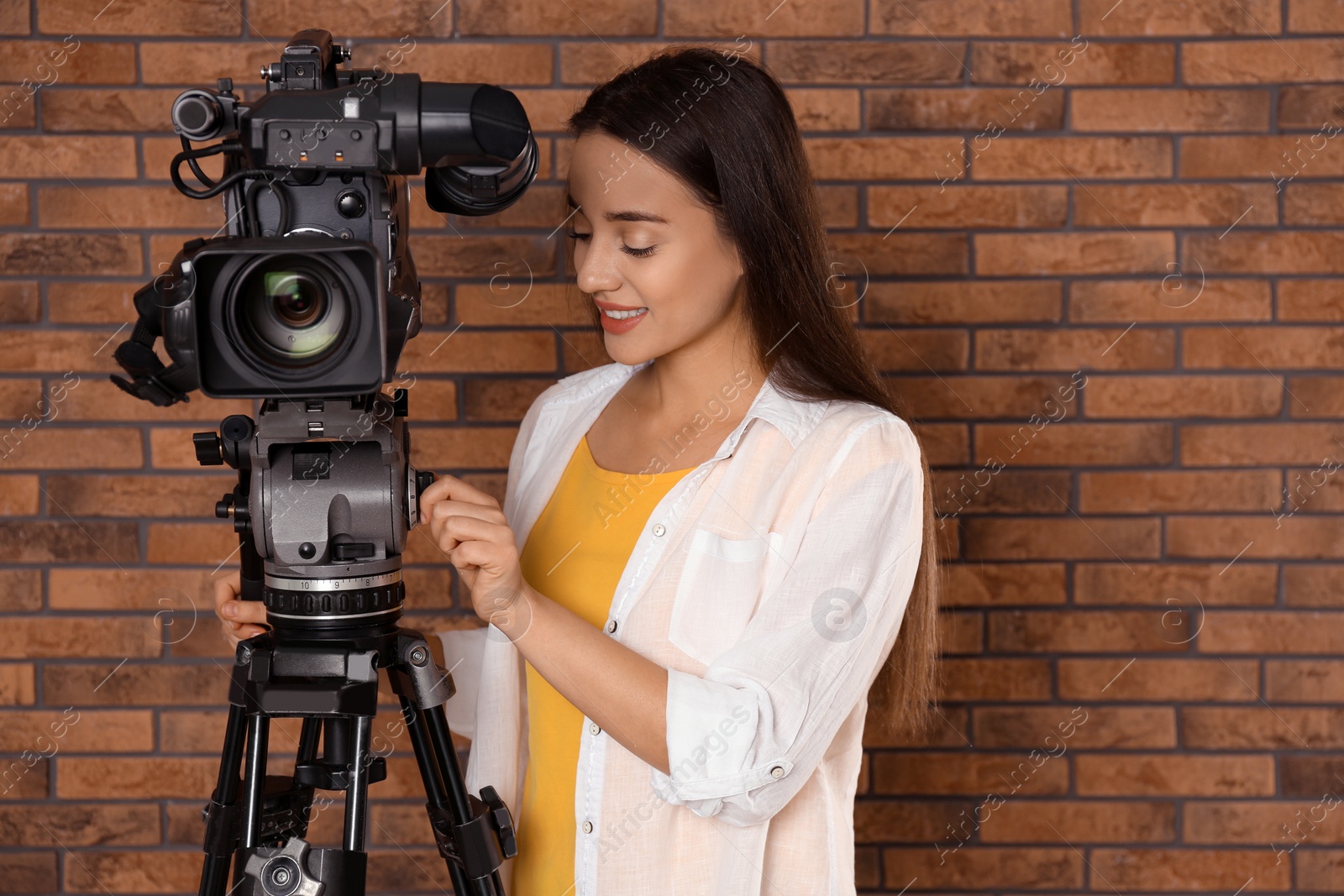 Photo of Operator with professional video camera near brick wall