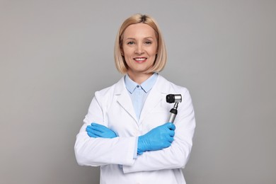 Photo of Happy dermatologist with dermatoscope on grey background