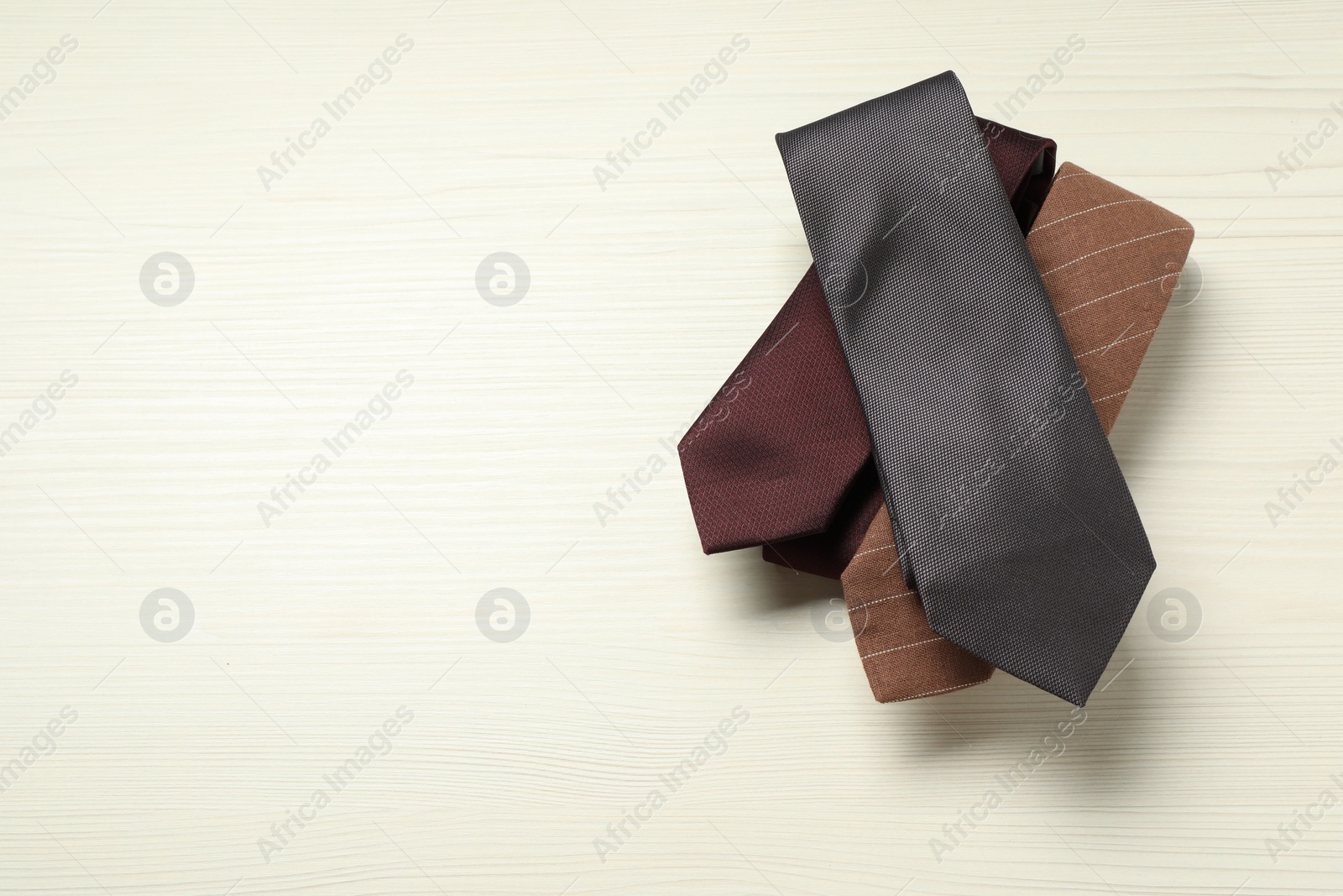 Photo of Different neckties on white wooden table, top view. Space for text