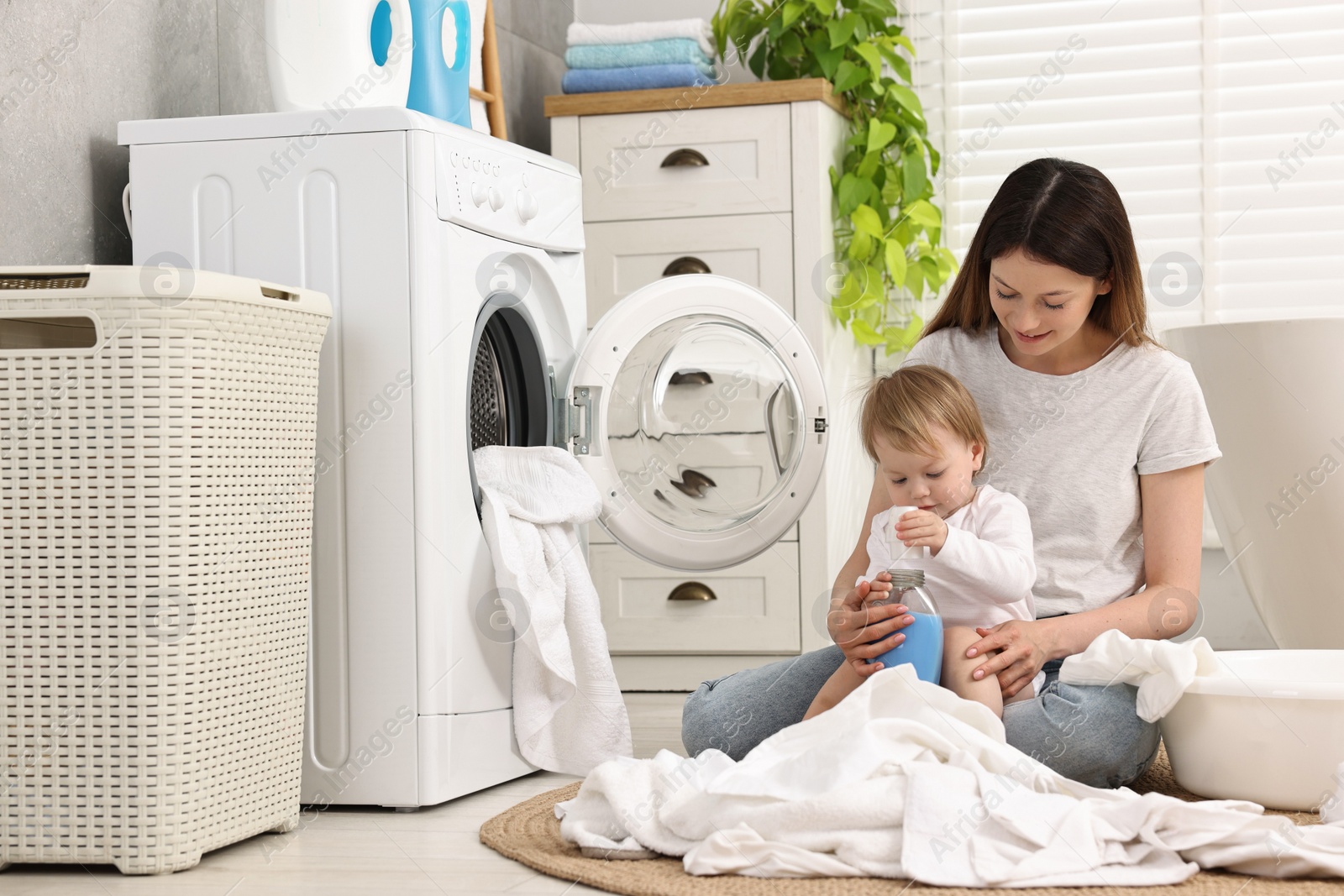 Photo of Mother with her daughter washing baby clothes in bathroom