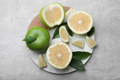 Photo of Whole and cut sweetie fruits on grey table, top view