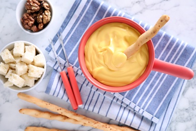 Flat lay composition with pot of cheese fondue and products on marble table