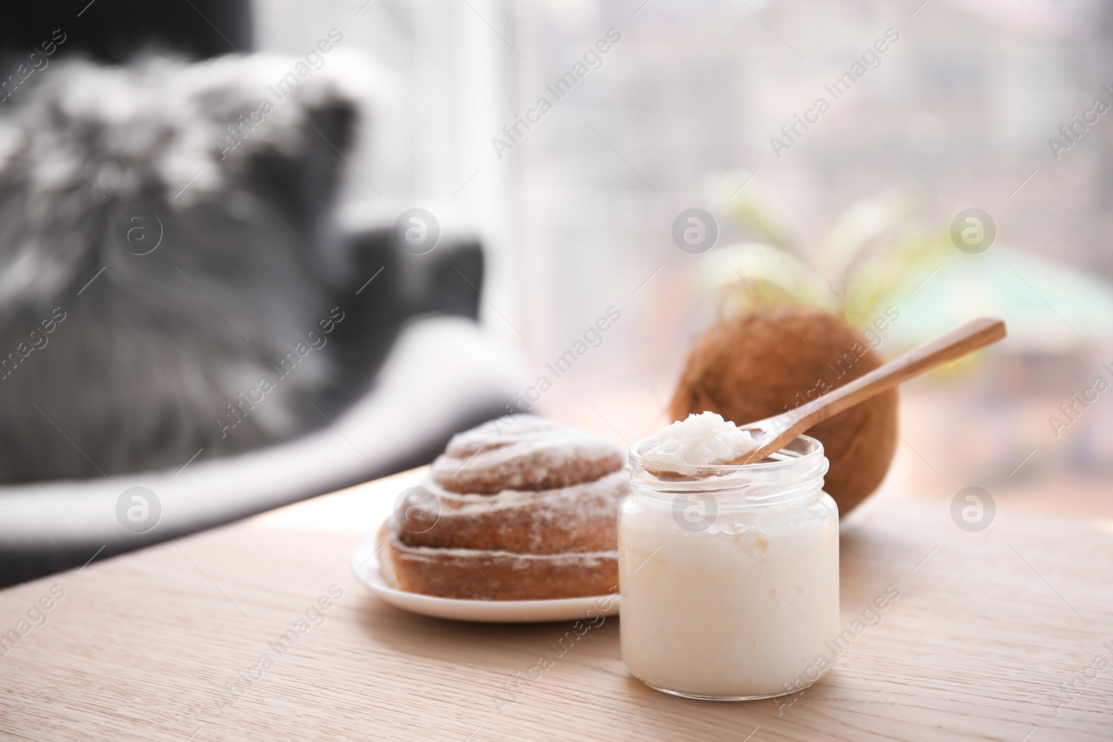 Photo of Wooden spoon and jar with coconut oil on table. Healthy cooking