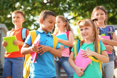 Cute little children with backpacks and notebooks outdoors. Elementary school