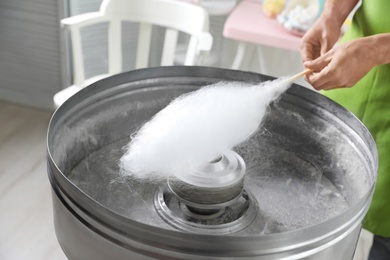 Woman making cotton candy using modern machine indoors, closeup