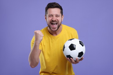 Photo of Emotional sports fan with ball celebrating on purple background