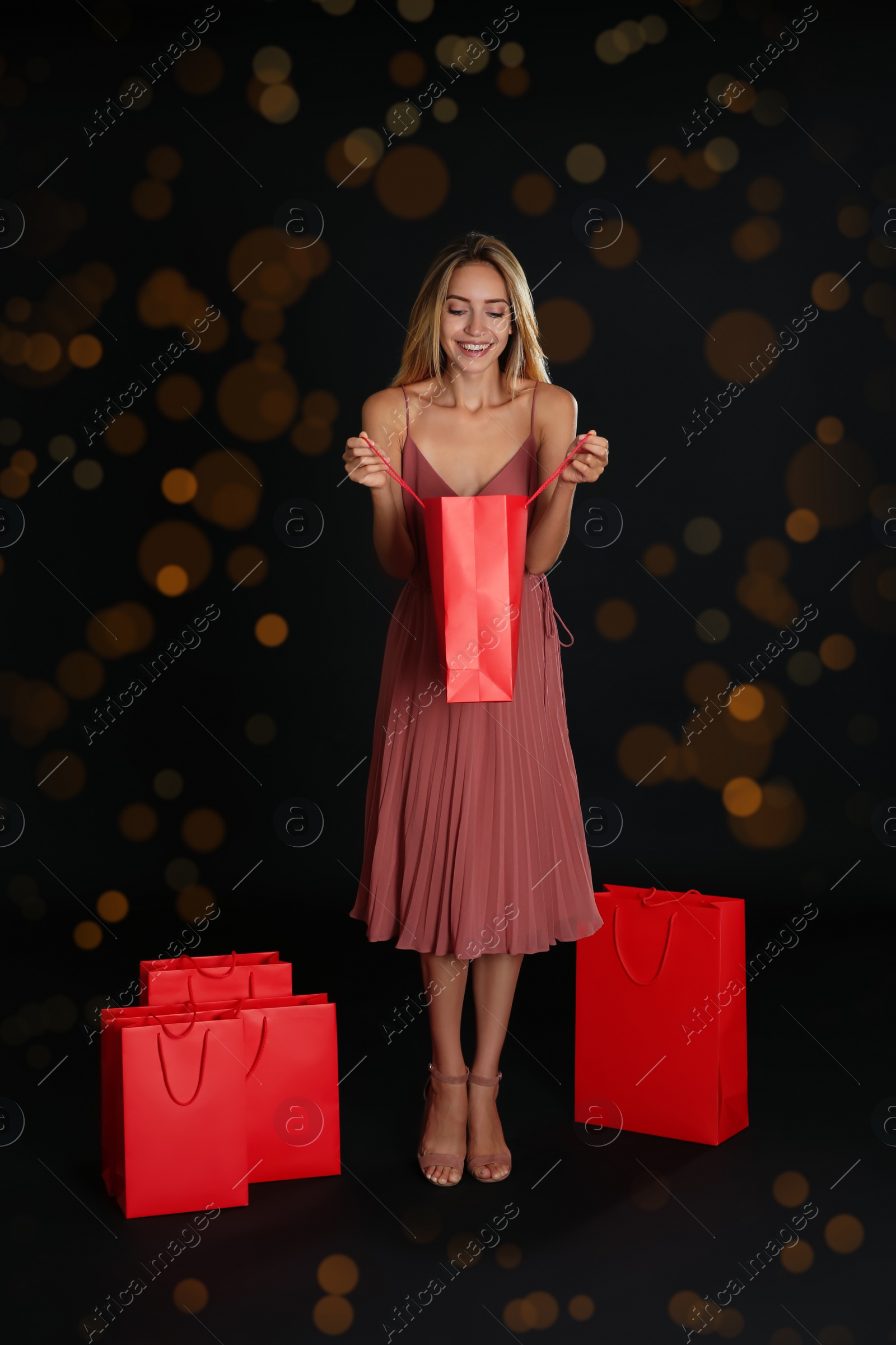 Photo of Happy young woman with shopping bags on dark background. Black Friday Sale