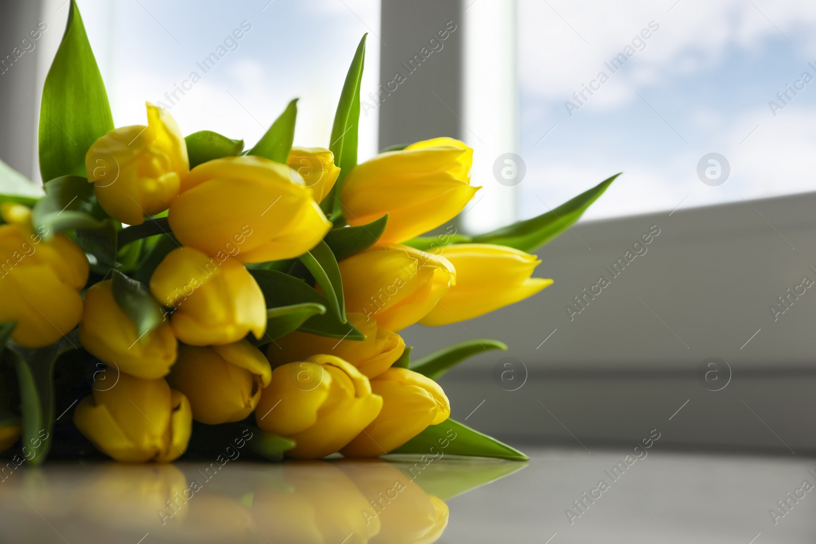 Photo of Bunch of beautiful yellow tulip flowers on windowsill, closeup