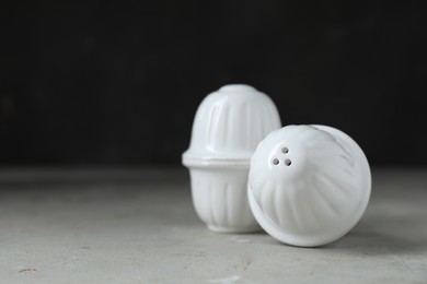 Photo of Salt and pepper shakers on light table against black background. Space for text