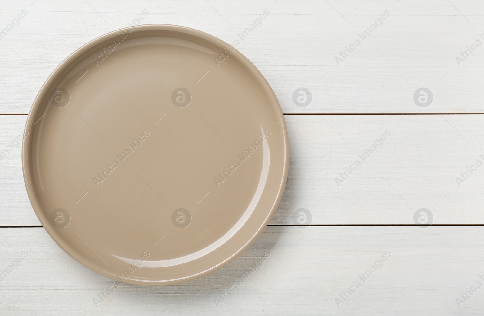 Photo of Empty ceramic plate on white wooden table, top view. Space for text