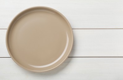 Empty ceramic plate on white wooden table, top view. Space for text