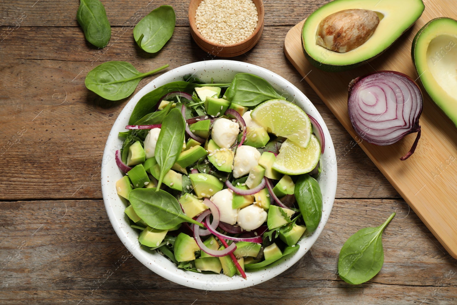 Photo of Delicious avocado salad with mozzarella on wooden table, flat lay