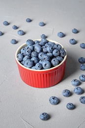 Crockery with juicy and fresh blueberries on color table