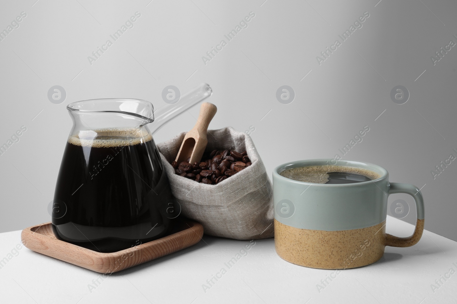 Photo of Turkish coffee. Glass cezve, cup and bag of beans on white table