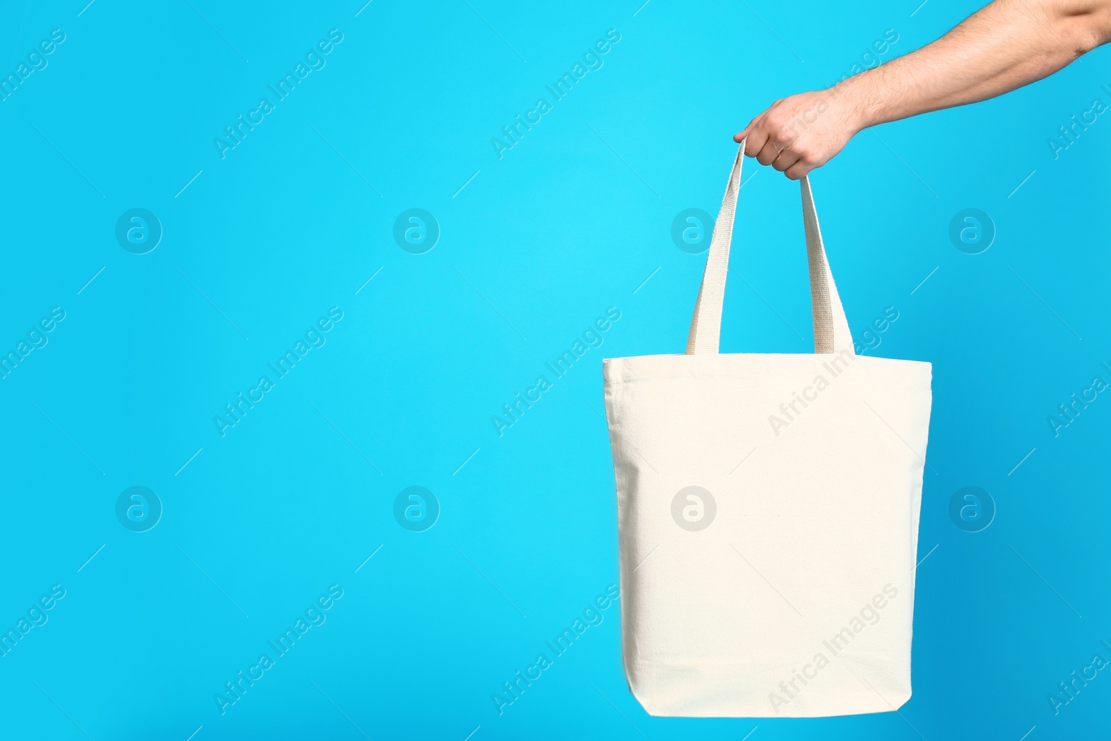 Photo of Young man with eco bag on blue background, closeup. Space for text