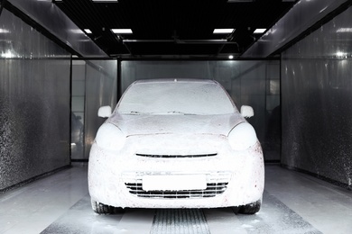 Photo of Auto covered with foam at car wash. Cleaning service