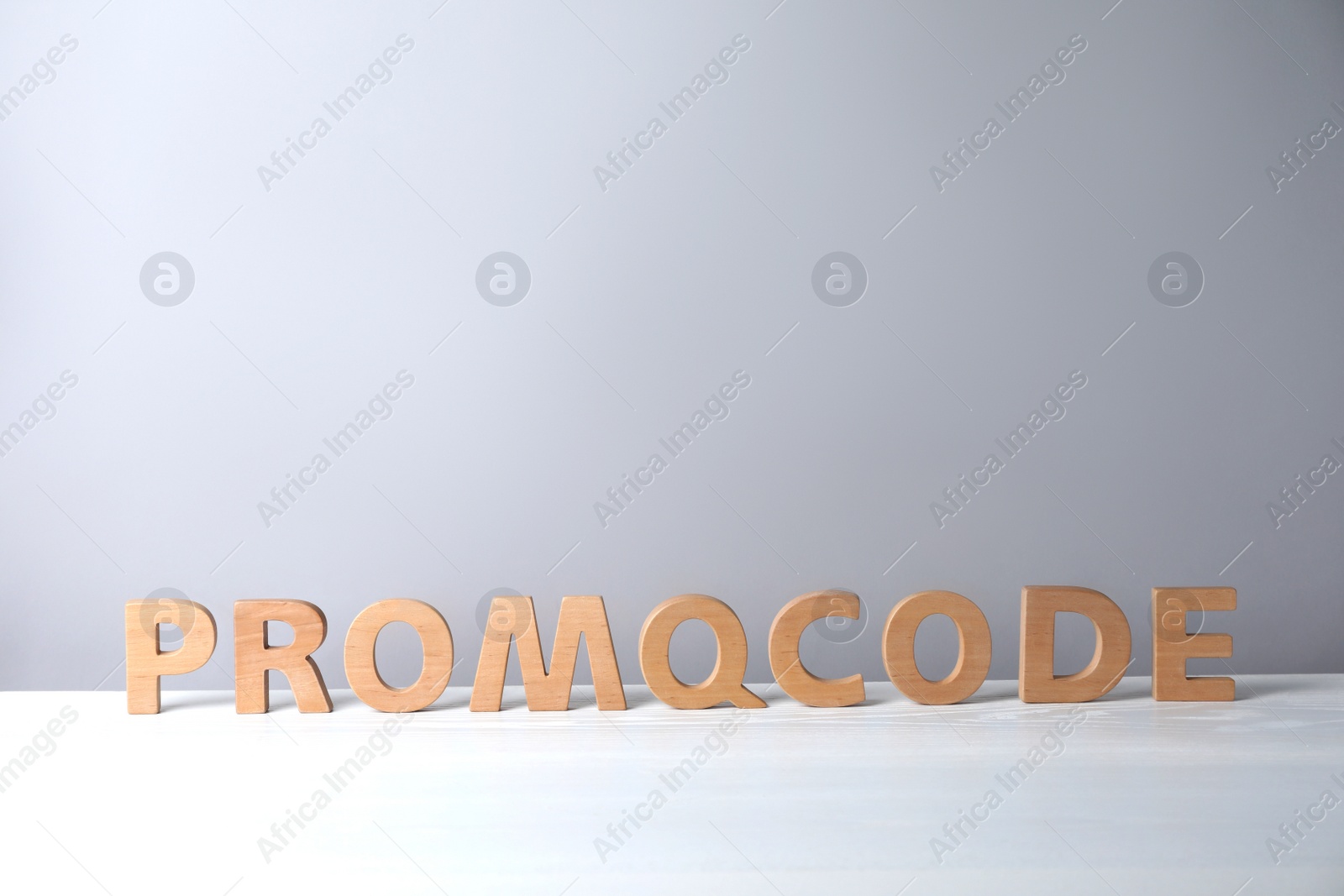 Photo of Words Promo Code made of wooden letters on white table, space for text